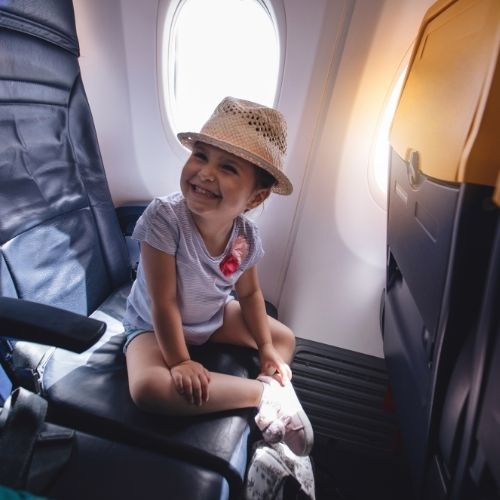toddler on plane sitting with hat on and smiling