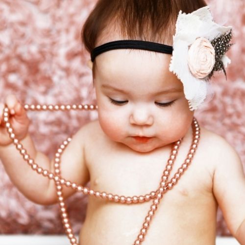 little girl wearing pink pearls and headband