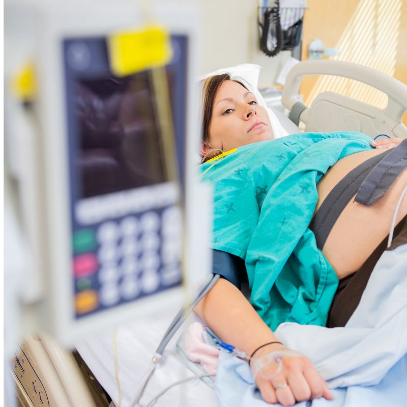 epidural pump and pregnant woman behind wearing monitors lying down after epidural