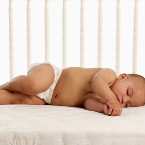 baby sleeping in diaper inside crib