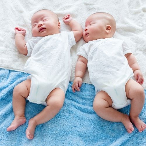 twin boys japanese laying on blue and white blanket