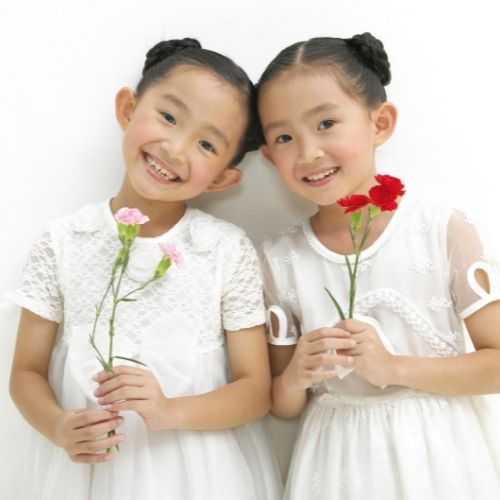 two girls with buns holding flowers and smiling