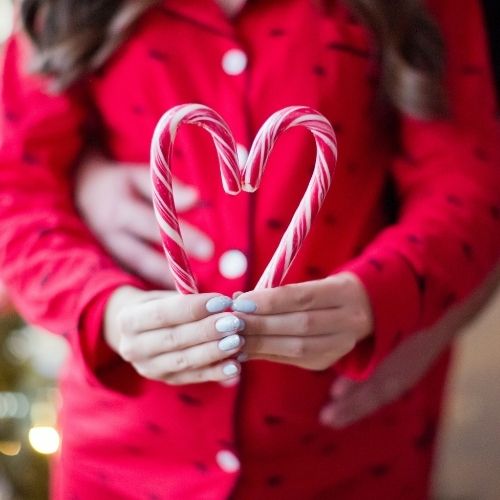 pregnant woman holding candy canes shaped like heart
