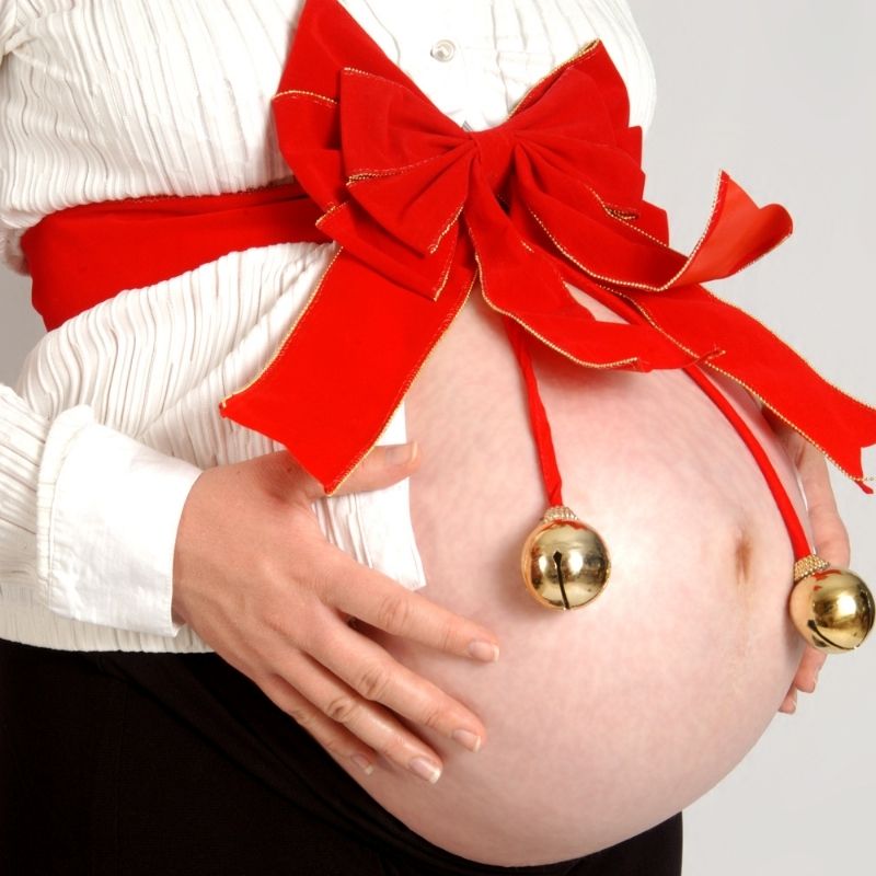 pregnant belly wrapped with christmas bow