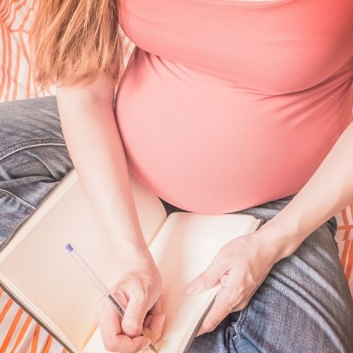 what to put on a birth plan, pregnant person writing in a notebook