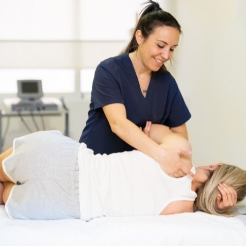 pregnant woman laying on side while female chriopractor adjusts upper back