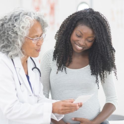 pregnant woman standing with doctor looking over results