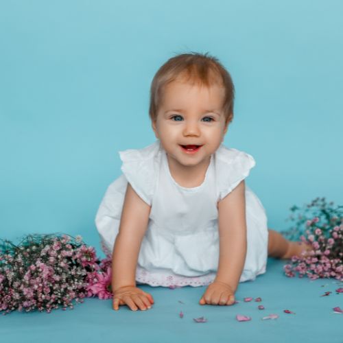 baby girl with blue background surrounded by flowers