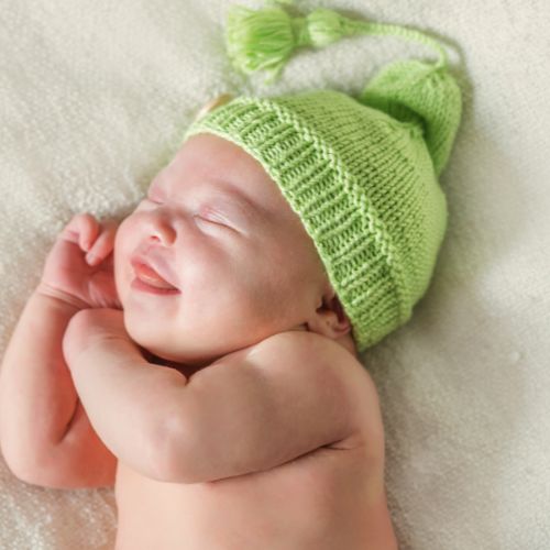 baby boy smiling sleeping in green hat rolling softly to right side