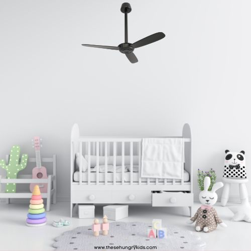 neutral nursery crib in background with blanket over rail, toys on floor like stuffed animals and blocks, a ceiling fan overhead