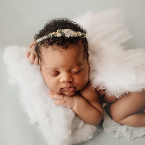 baby girl laying on tummy wearing a headband and angel wings