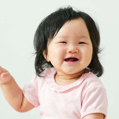 Asian baby girl smiling sitting upright with medium length hair