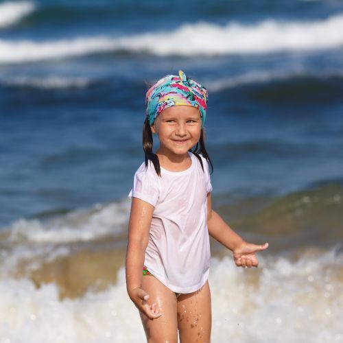young girl standing in front of ocean wet and smiling