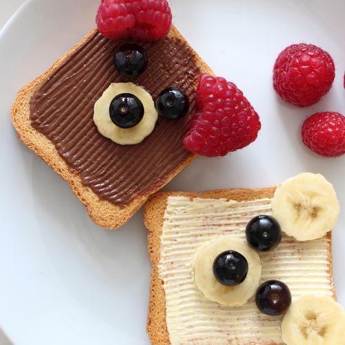 toast with berries and banana on top in the shape of a bear face with nutella and butter 