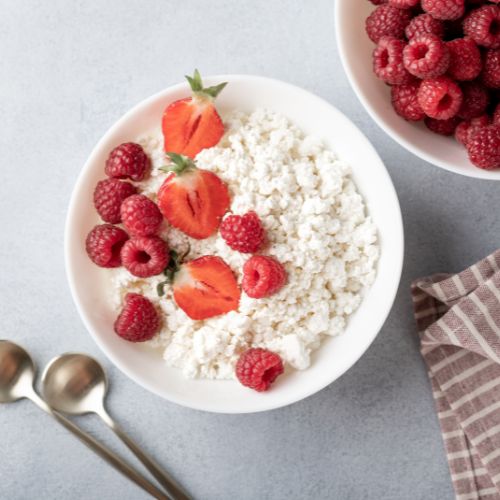 bowl with cottage cheese and raspberries and sliced strawberries