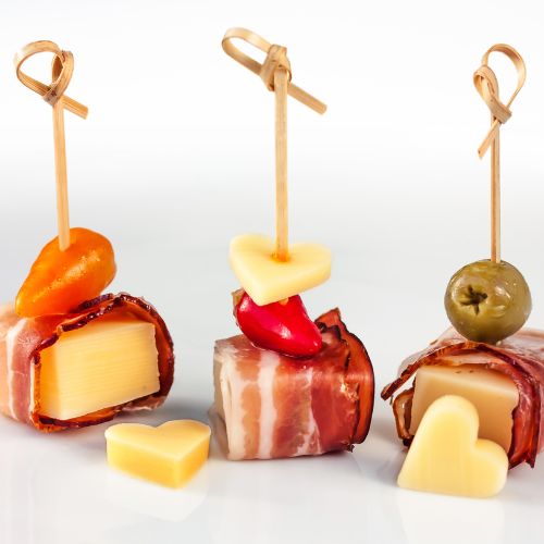 three bite sized toothpick skewers with cheese, prosciutto and an olive 