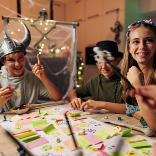 kids wearing costumes and masks sitting together playing a card game