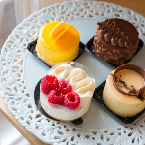 four unique small desserts arranged on a decorative plate in a circle