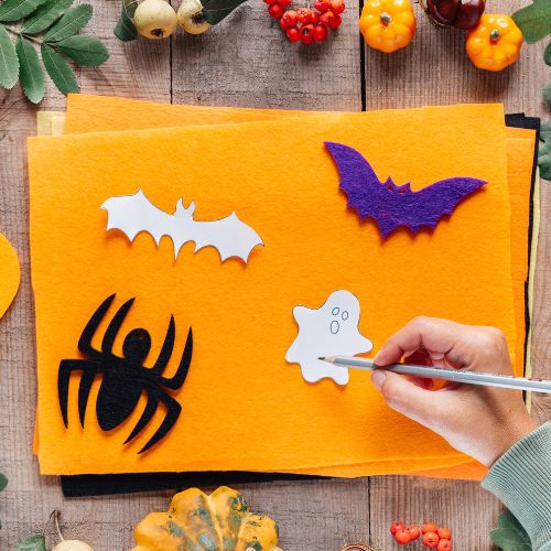 halloween shapes like cats and bats being traced onto orange felt