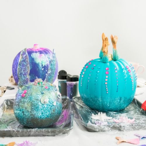 three pumpkins painted in teals and purples with glitter and gems glued on