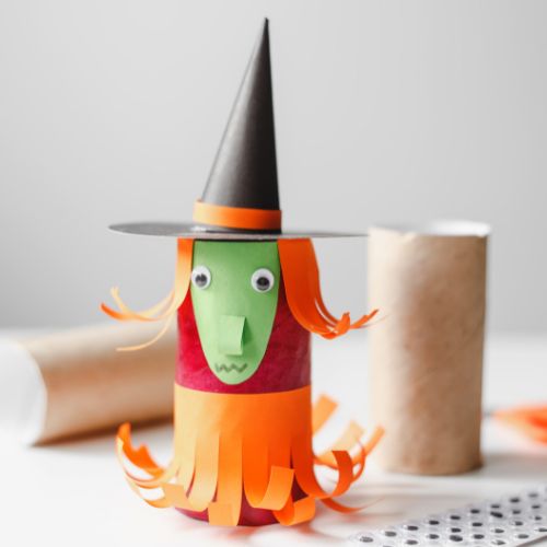 construction paper used to make a halloween witch decoration on toilet paper rolls with empty toilet paper rolls laying in background