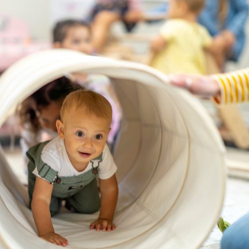 small child crawling through a fabric toy tunnel 